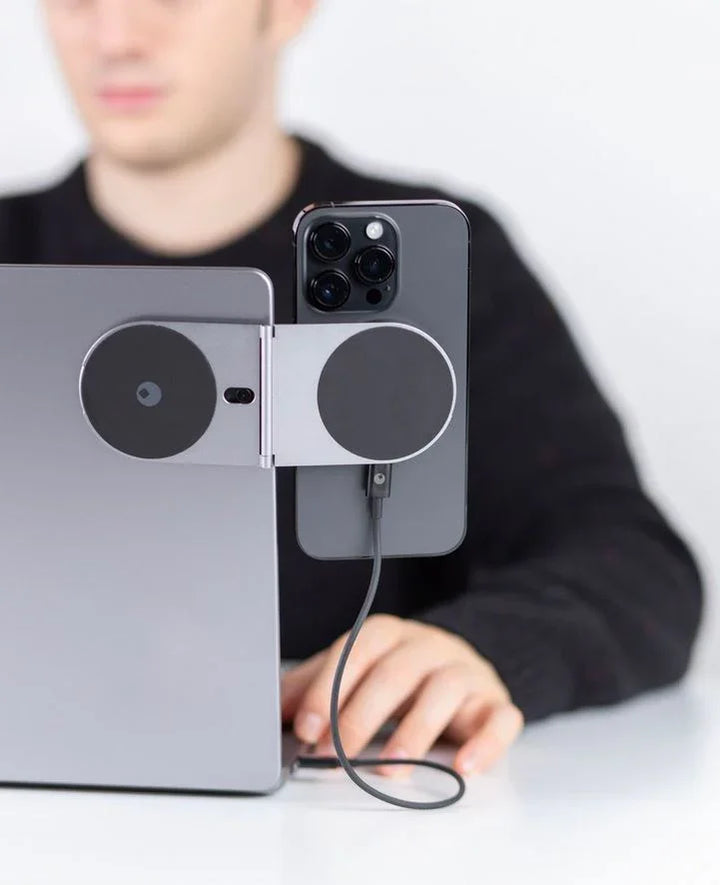 Magnetische Handyhalterung mit Ladekabel am Laptop, moderner Arbeitsplatz